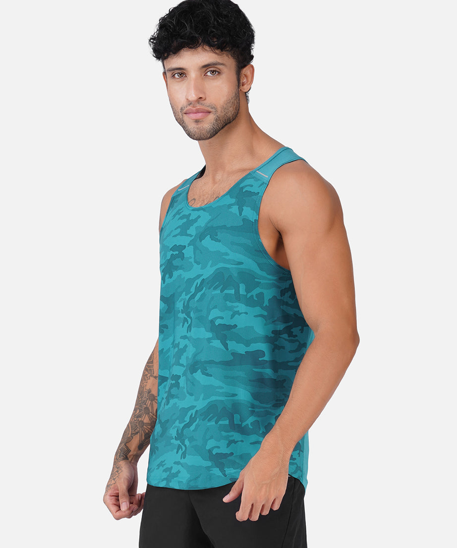 A man wearing a teal and dark blue camouflage-patterned athletic tank top, paired with black shorts, standing against a light gray background.
