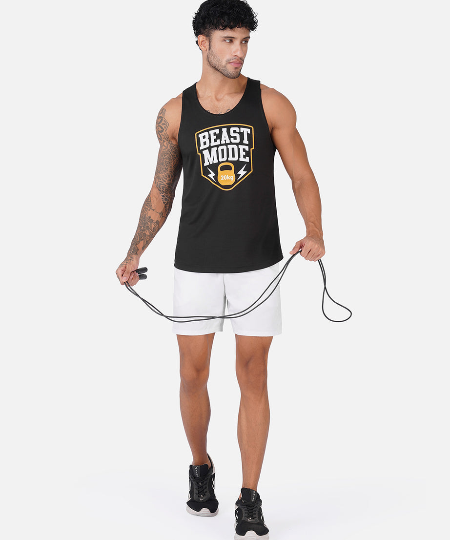 A man modeling a black tank top with a 'BEAST MODE' graphic, paired with white athletic shorts and black sneakers, holding a jump rope against a light gray background.