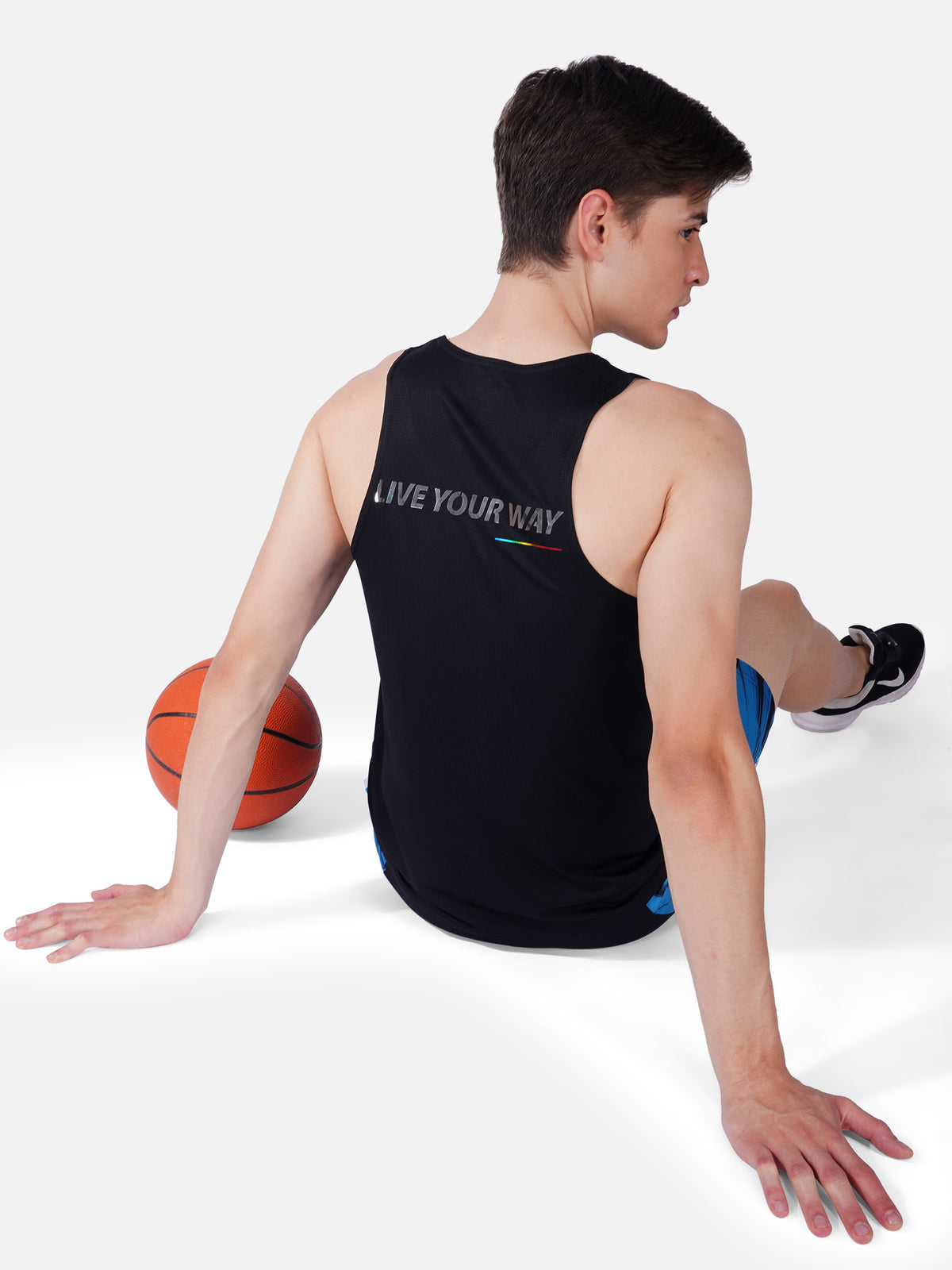 A man wearing a black sleeveless tank top with a printed text 'Live Your Way' on the front.