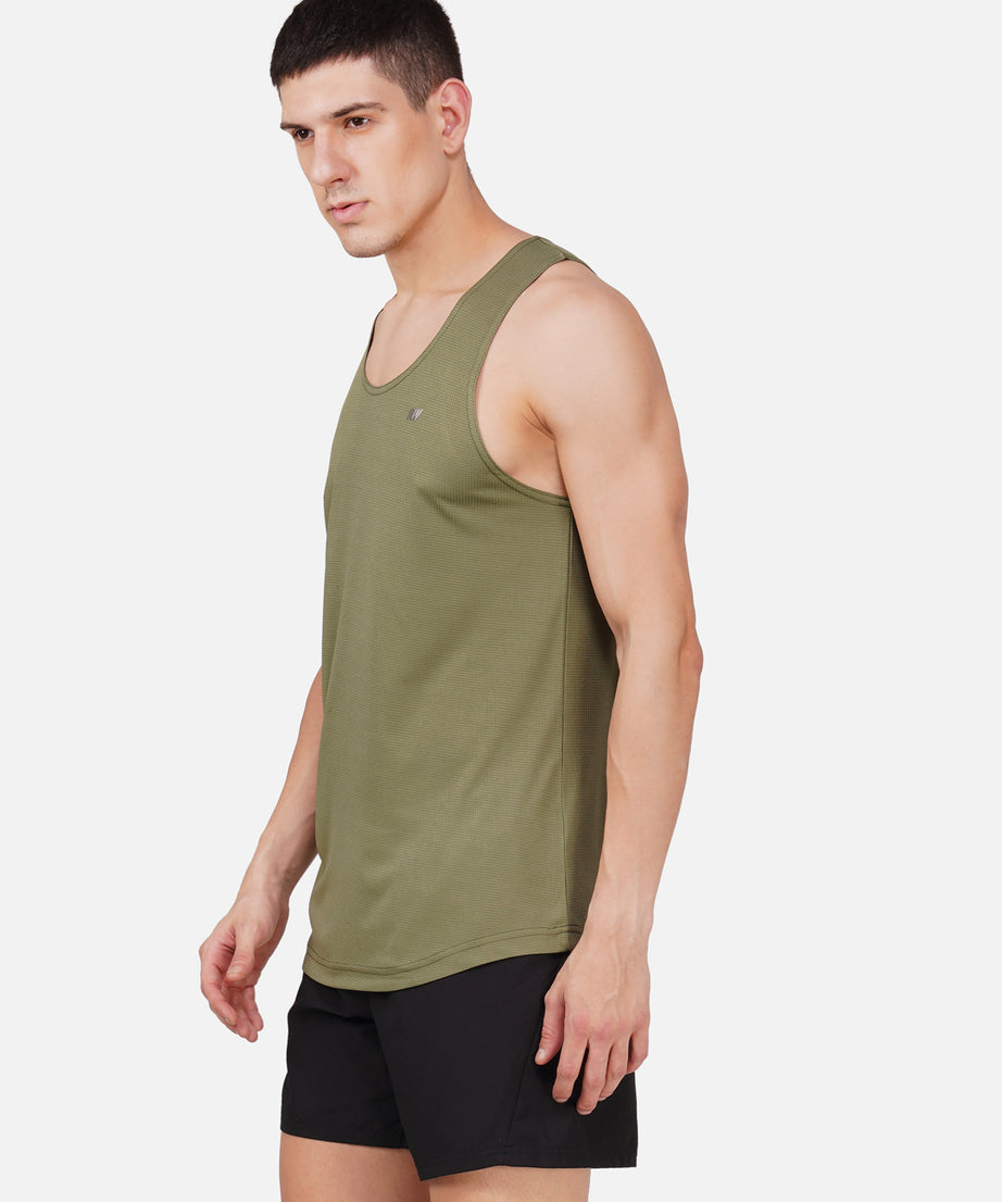 A man wearing a green solid color sleeveless vest with a round neckline.
