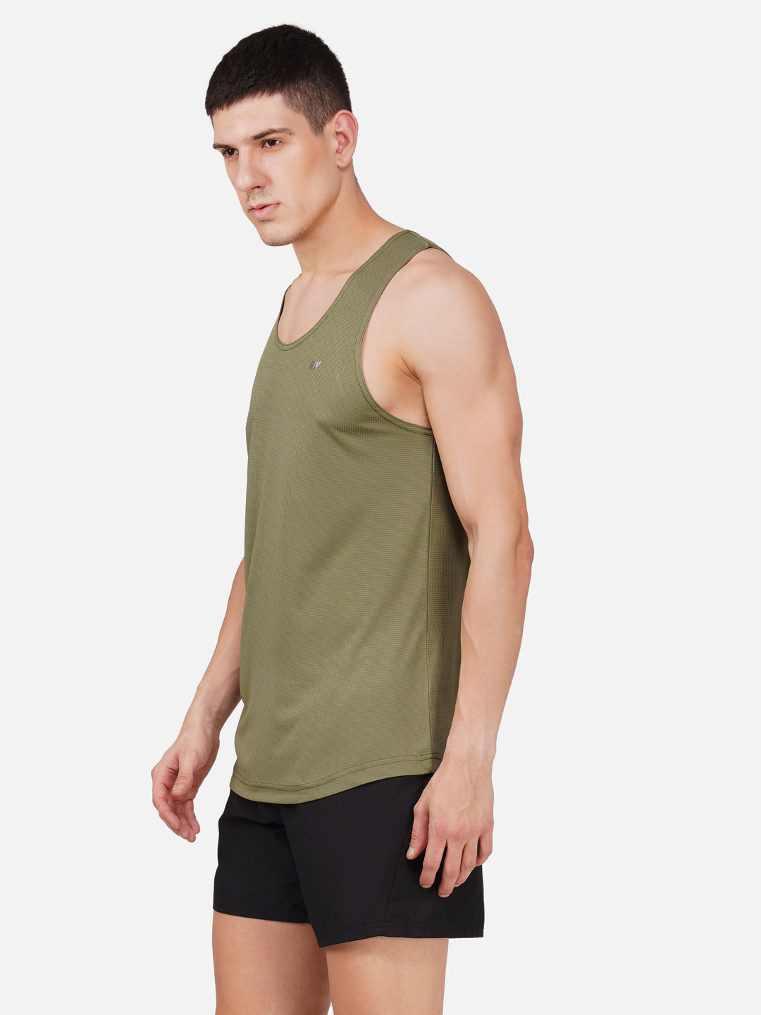 A man wearing a green solid color sleeveless vest with a round neckline.