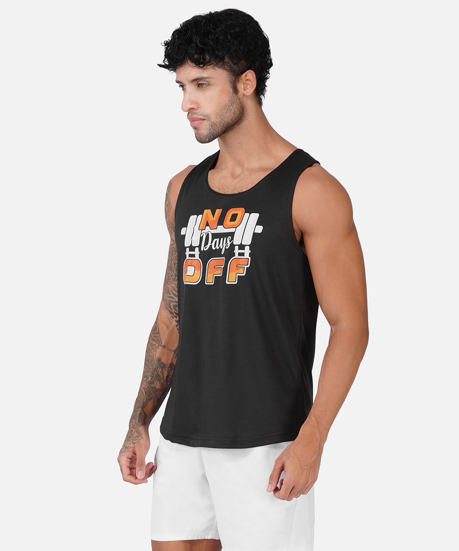 A man wearing a black sleeveless tank top with a white and orange graphic that reads 'No Days Off' with a barbell design, paired with white shorts, against a light gray background.
