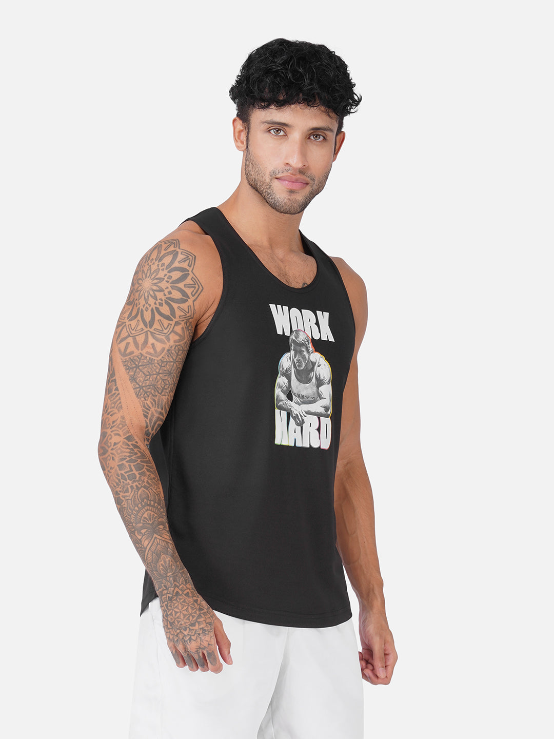 A man wearing a black sleeveless tank top with a white graphic print that reads 'WORK HARD' and a photo of a muscular man, paired with white pants, against a light gray background.