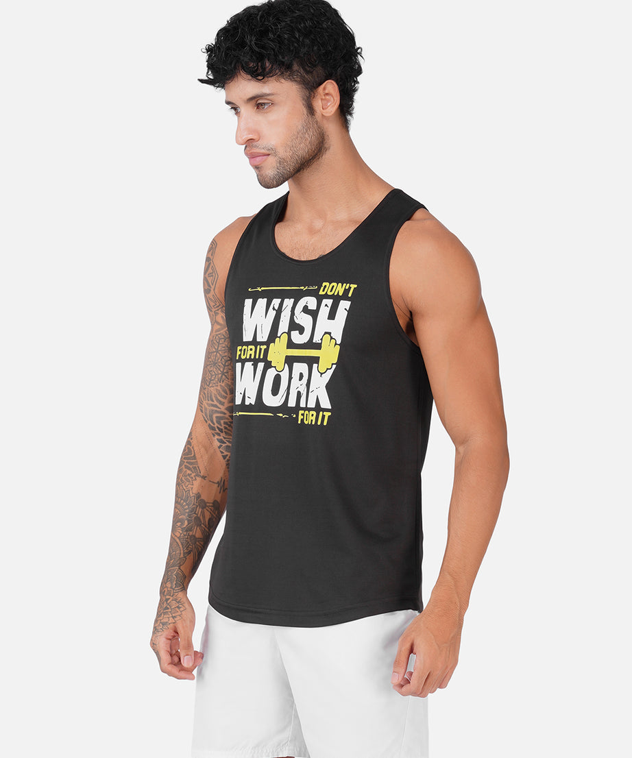 A man wearing a black sleeveless tank top with a yellow and white graphic that reads 'DON'T WISH YOU WORK FOR IT' paired with white shorts, set against a plain light gray background.
