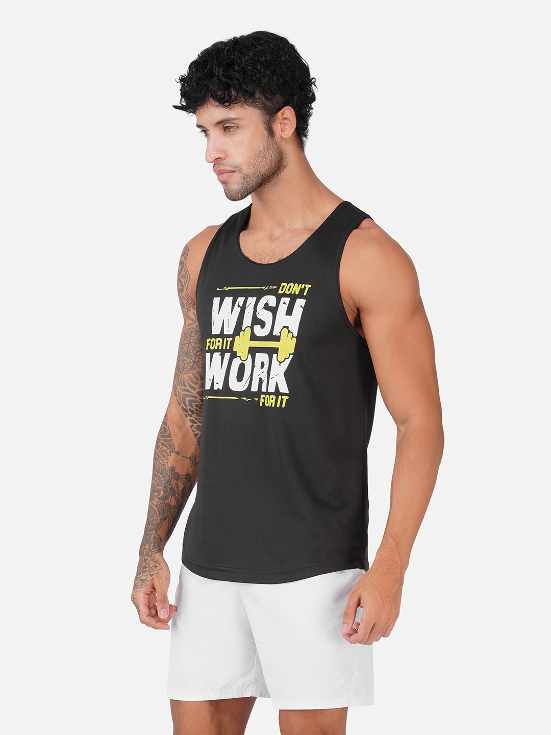 A man wearing a black sleeveless tank top with a yellow and white graphic that reads 'DON'T WISH YOU WORK FOR IT' paired with white shorts, set against a plain light gray background.